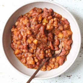 Close up of baked beans in a bowl with a spoon.