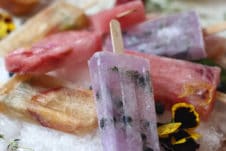 Homemade popsicles on a bed of ice on a wooden plate.