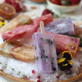 Homemade popsicles on a bed of ice on a wooden plate.