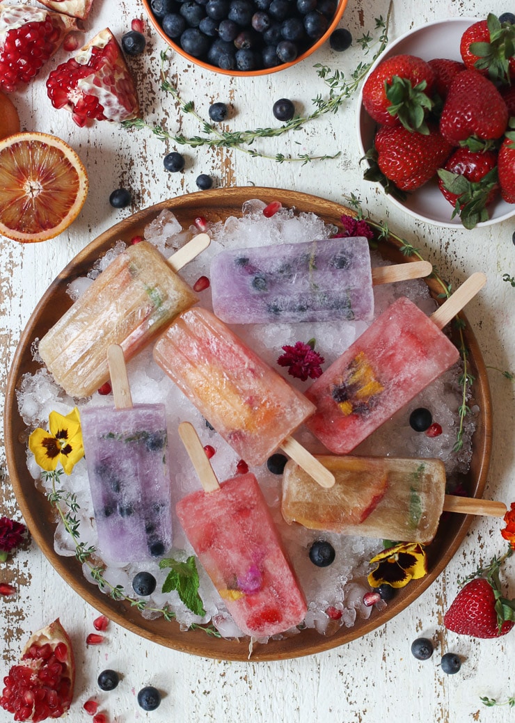 Homemade fruit popsicles made with kombucha on a bed of ice on a wooden plate.