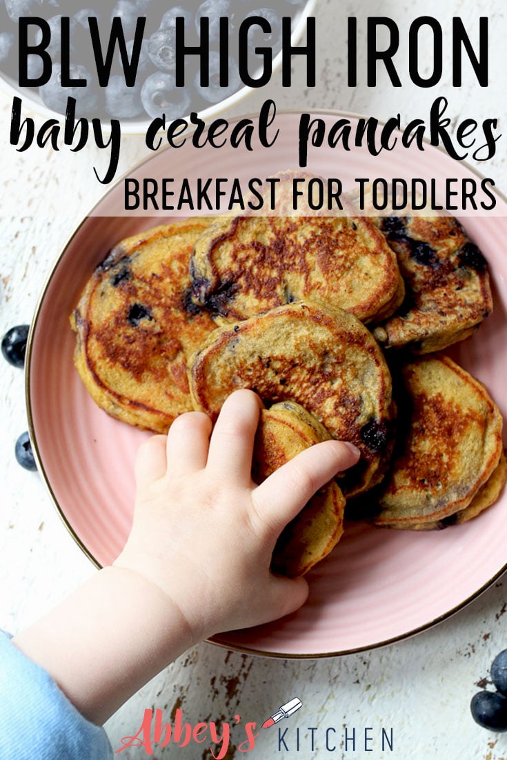 pinterest image of baby hand reaching for cereal protein pancakes on a pink plate with text overlay