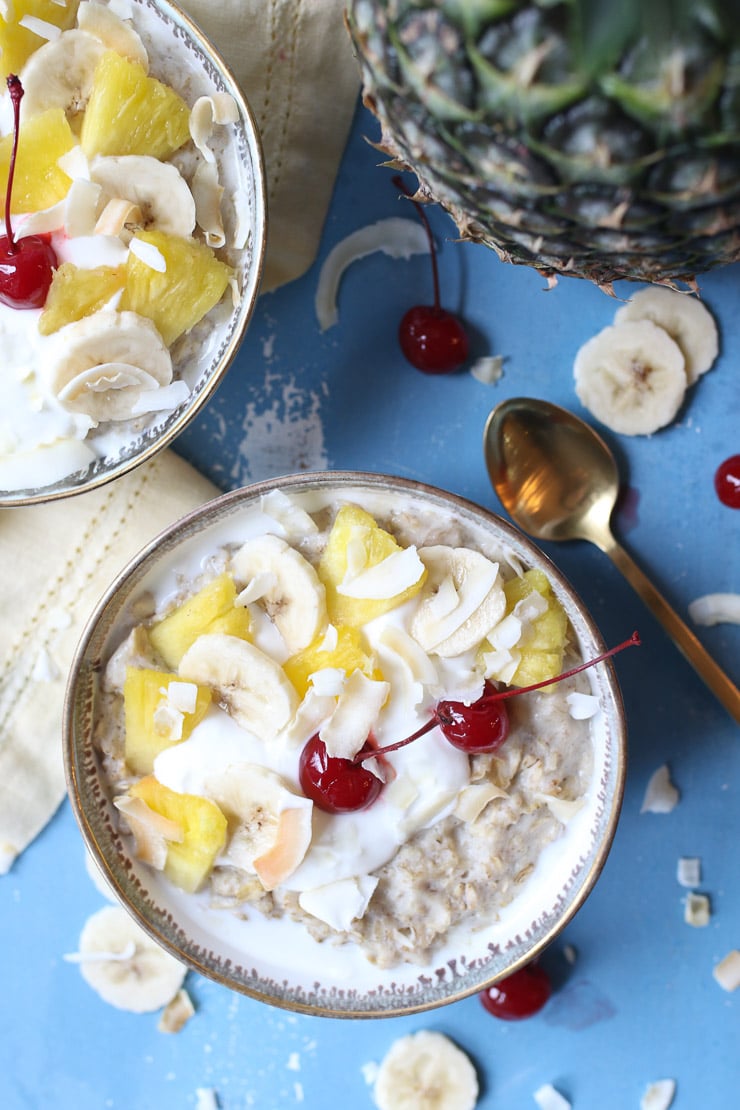 Bowl of pineapple oatmeal topped with pineapple, cherries and yogurt. 