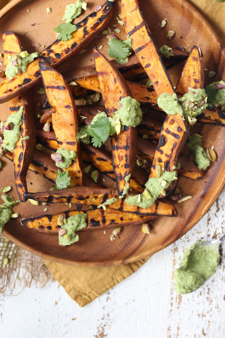 BBQ sweet potato on a wooden plate with avocado lime sauce 