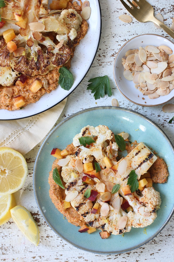 Grilled cauliflower steaks on a teal plate.