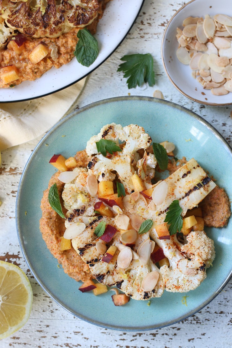 Grilled cauliflower steaks on a teal plate.