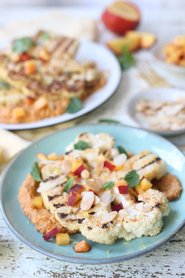 Grilled cauliflower steaks on a teal plate.