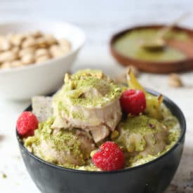 Pistachio green tea nice cream topped with fruit next to a bag of pistachios.