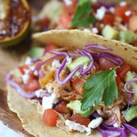 Pulled chicken tacos topped with slaw and cilantro.