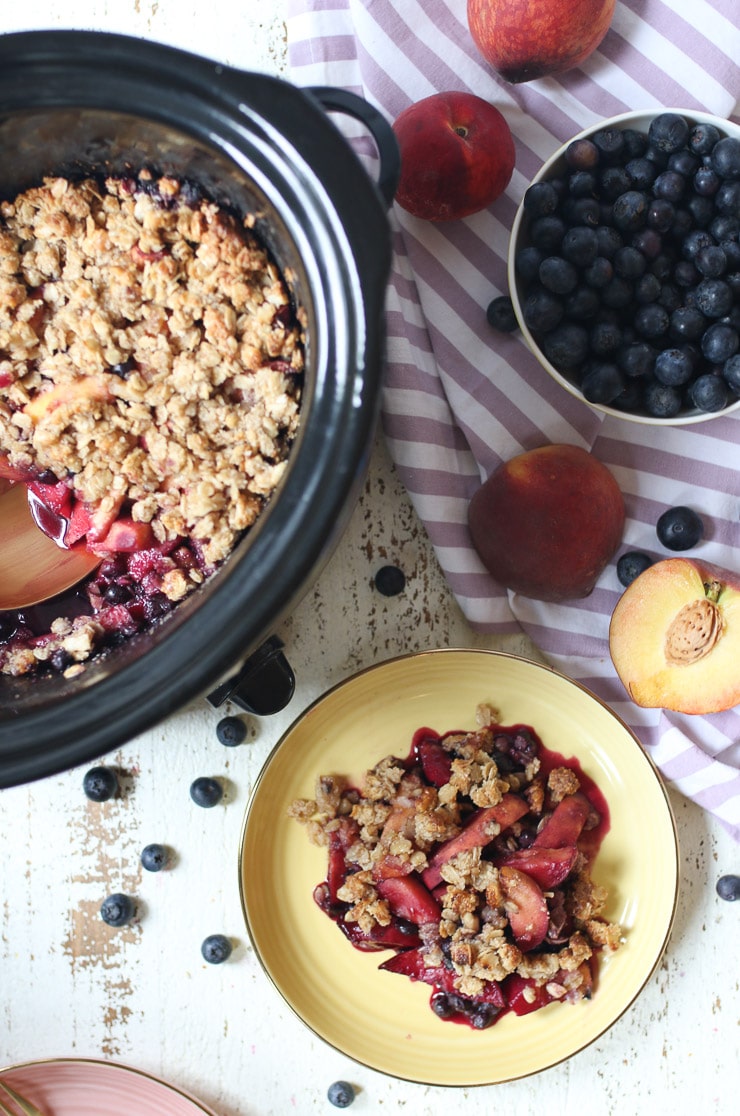 Blueberry and peach crisp on a plate and in a slow cooker.