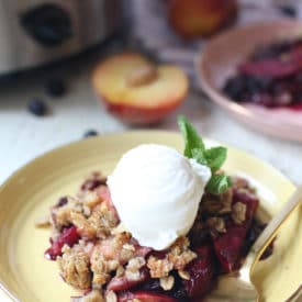 Fruit crisp on a yellow plate topped with ice cream.