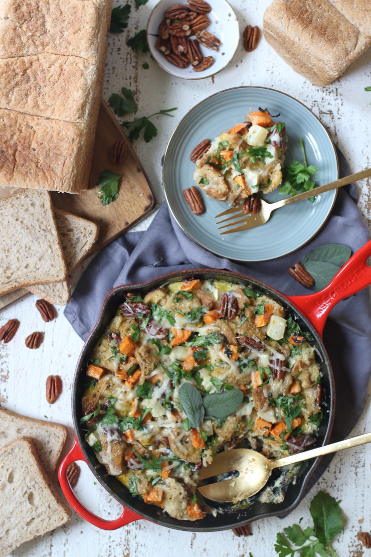 Vegetable strata served in skillet next to a serving plate.