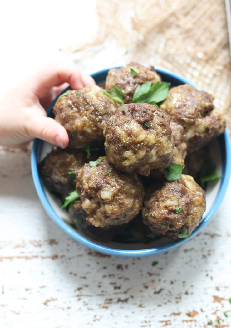 Baby grabbing toddler meatballs.