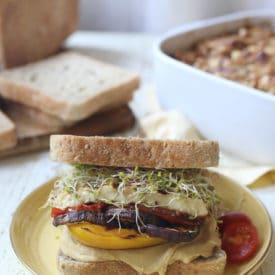 Veggie sandwich with hummus and halloumi served on a yellow plate.