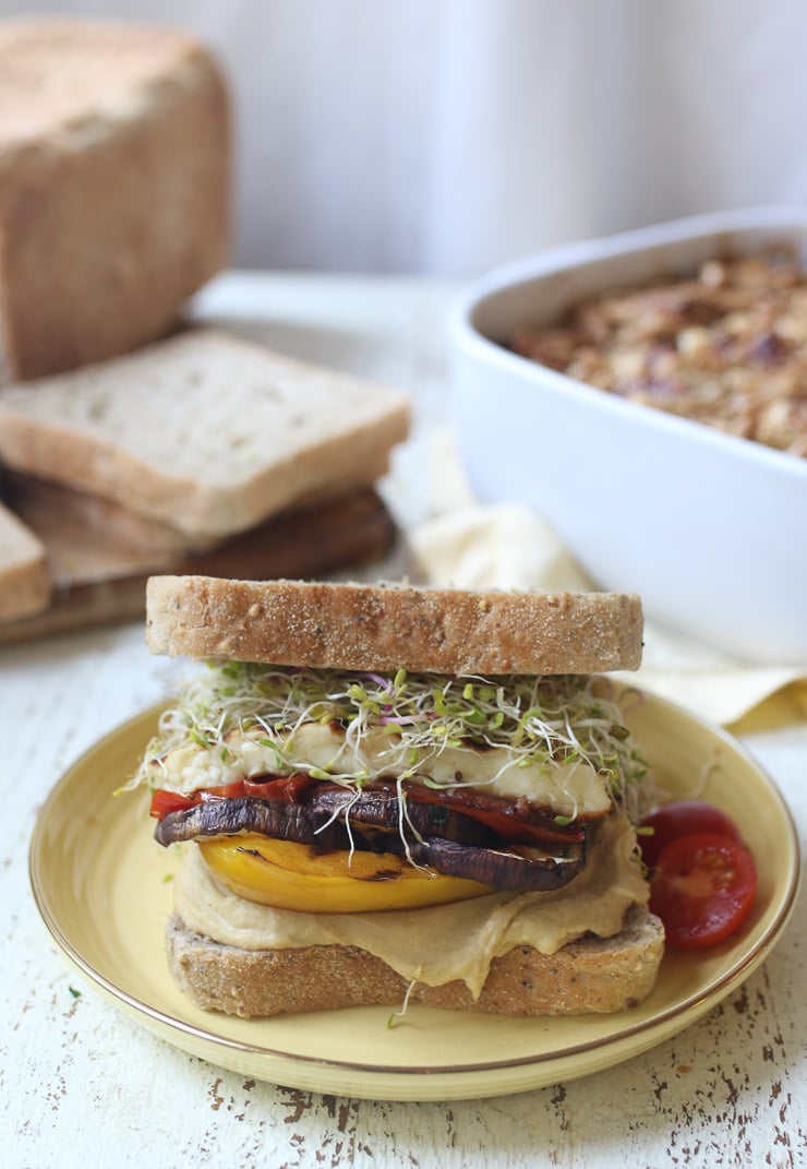 Veggie sandwich with hummus and halloumi served on a yellow plate.