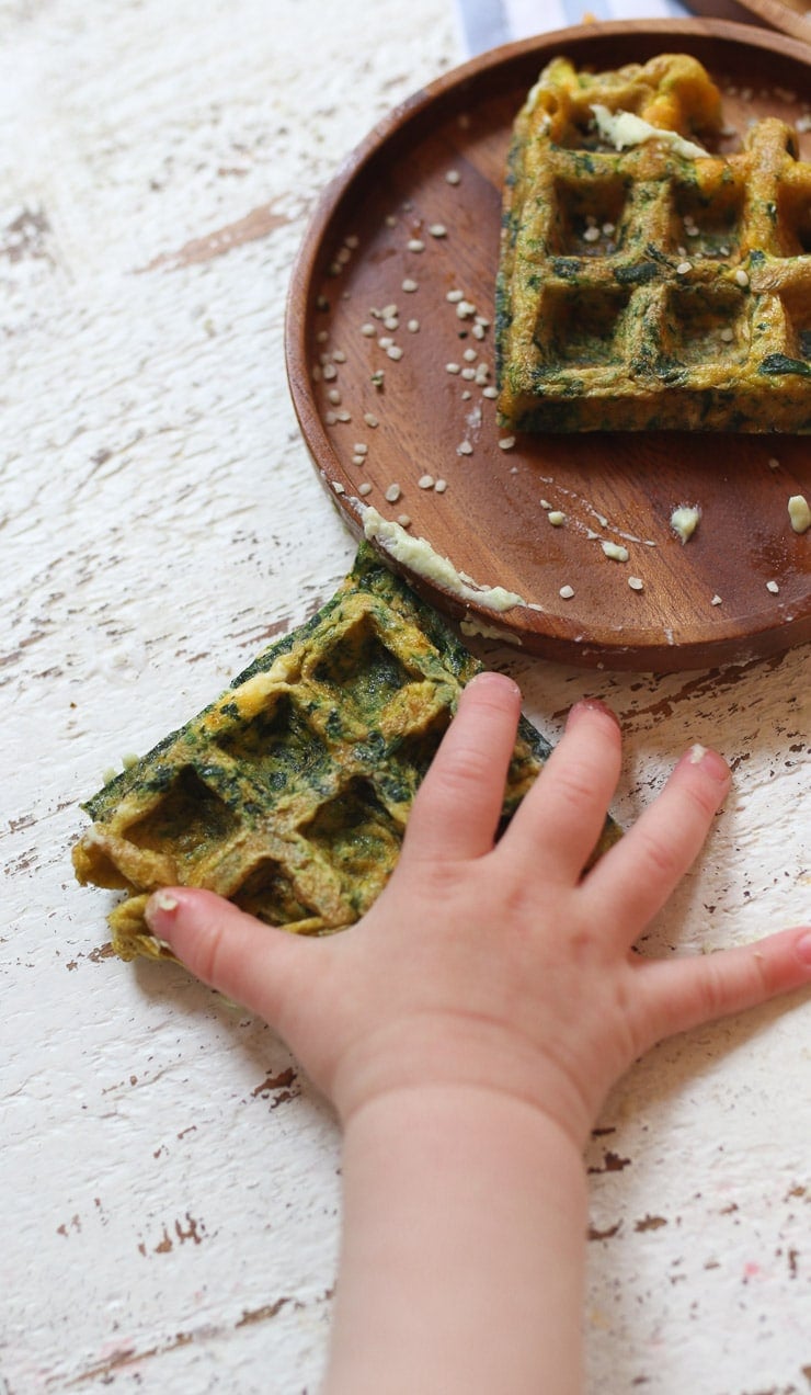 Baby hand holding an egg waffle.
