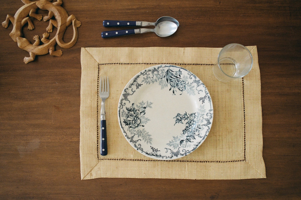 Plate setting with a floral plate and blue utensils. 