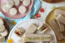 Finger sandwiches on several plates.