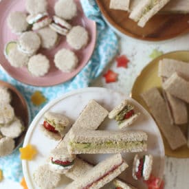 Finger sandwiches on several plates.