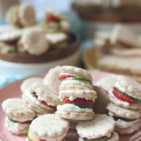 Strawberry and cucumber finger sandwiches on a pink plate.