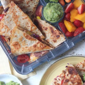 Quesadilla in a lunch box and served on a yellow plate.