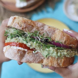 Hand holding large vegan sandwich.