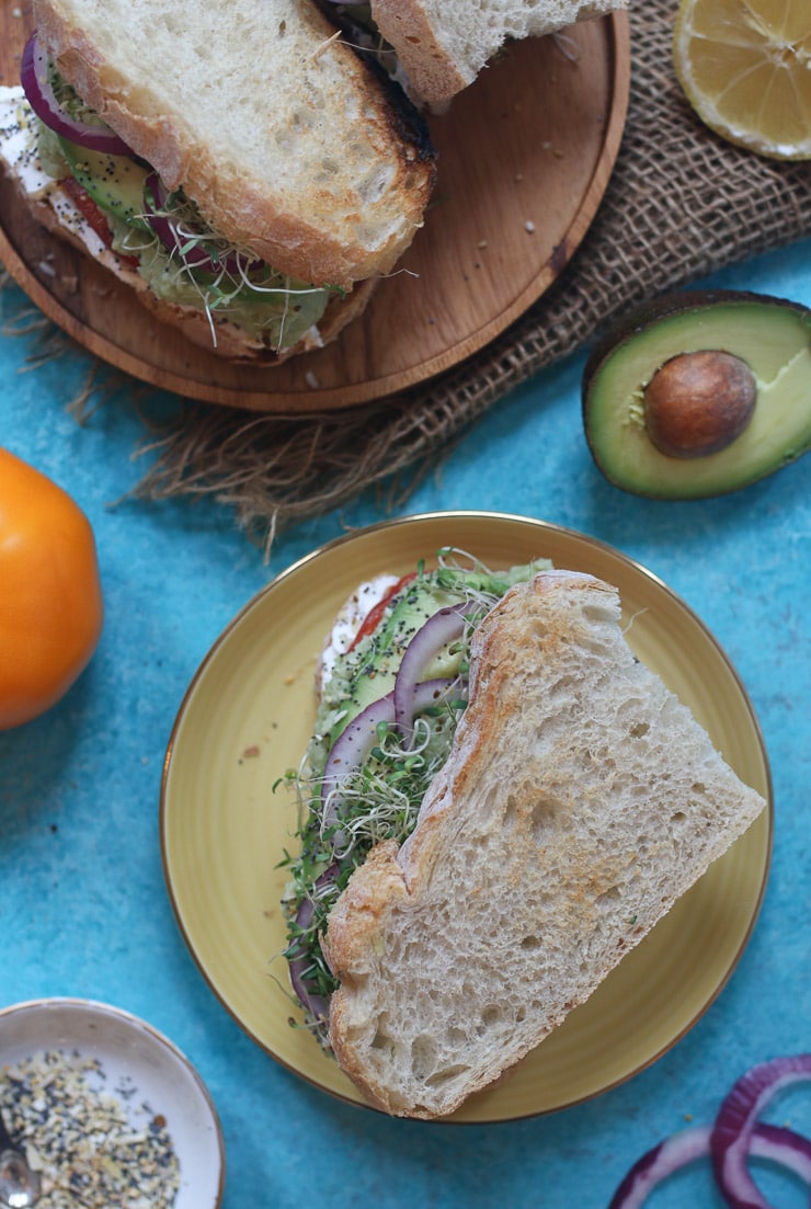 Two sandwiches on a yellow plate and brown plate.