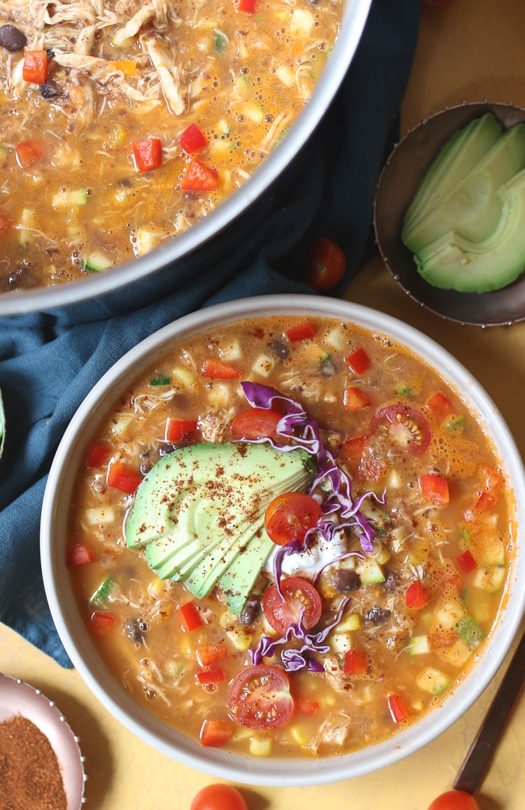 Tortilla soup in a large bowl topped with avocado and cabbage.