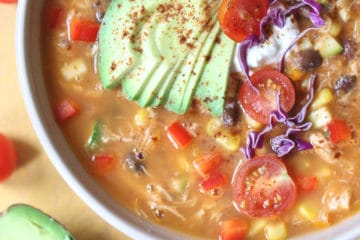Tortilla soup in a large bowl topped with avocado and cabbage.