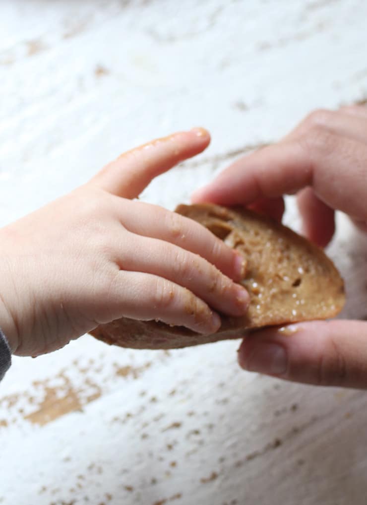 Baby's hand holding bread with peanut butter.