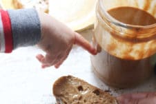 Baby's hand pointing to jar of peanut butter.