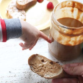 Baby's hand pointing to jar of peanut butter.