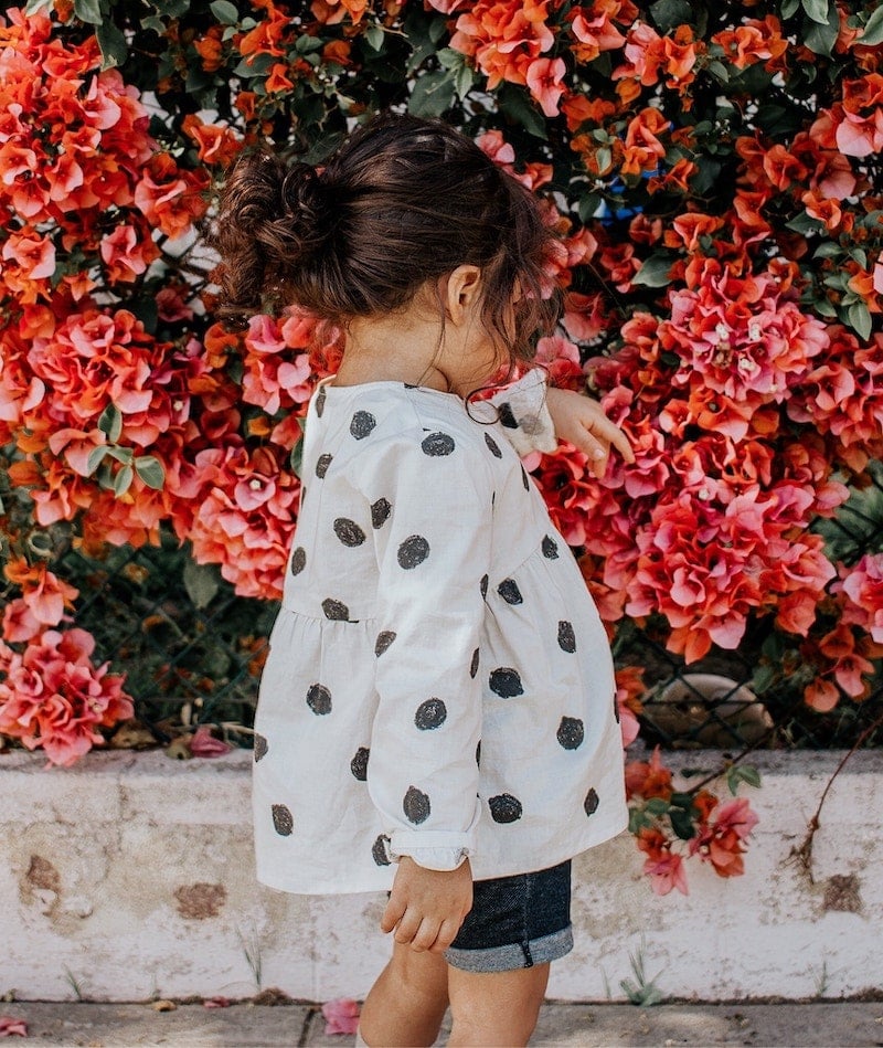 Young girl next to flowers.