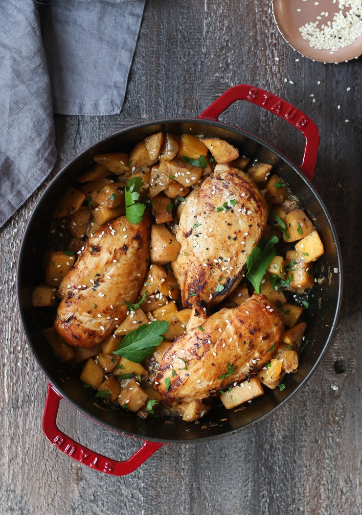 Birds eye view of one pot gluten free fruit flavoured chicken breasts in a red pot garnished with seeds