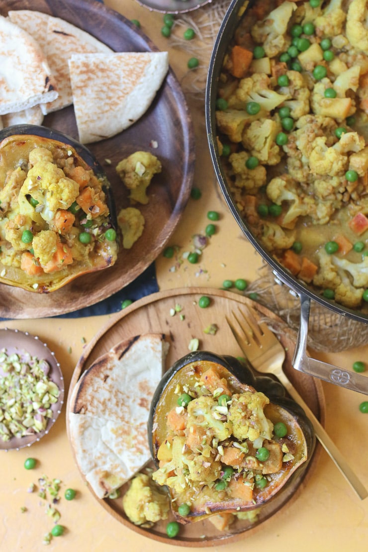 Coconut lentil curry garnished with pistachios served on wooden plate with naan.