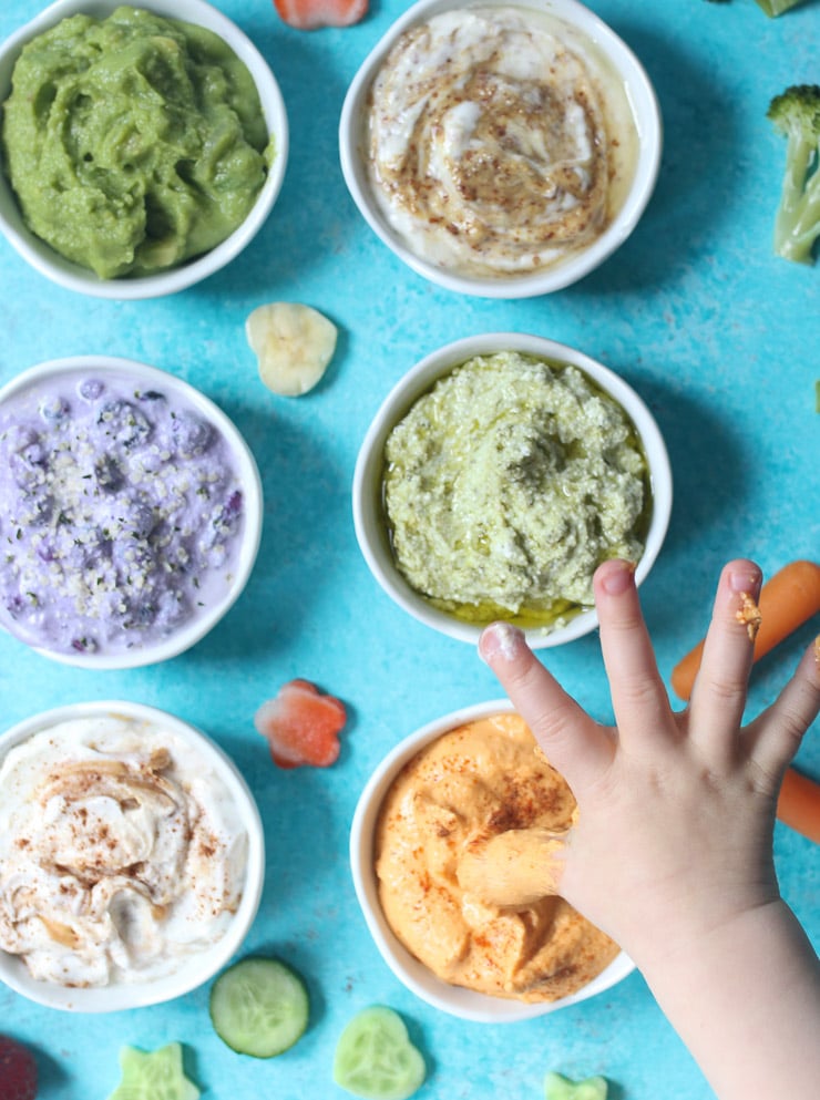toddler hands dipping into a variety of dips.