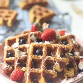 Carrot cake waffles served on a pink plate topped with berries.
