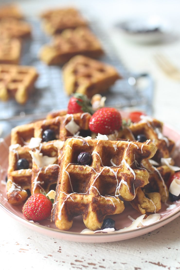 Carrot cake waffles served on a pink plate topped with berries. 