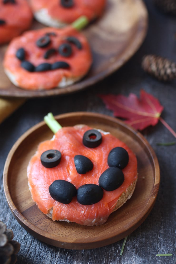 Close up of smoked salmon sandwich on a brown wooden plate. 