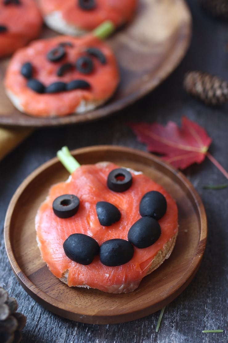 Close up of pumpkin smoked salmon sandwich on a brown wooden plate. 