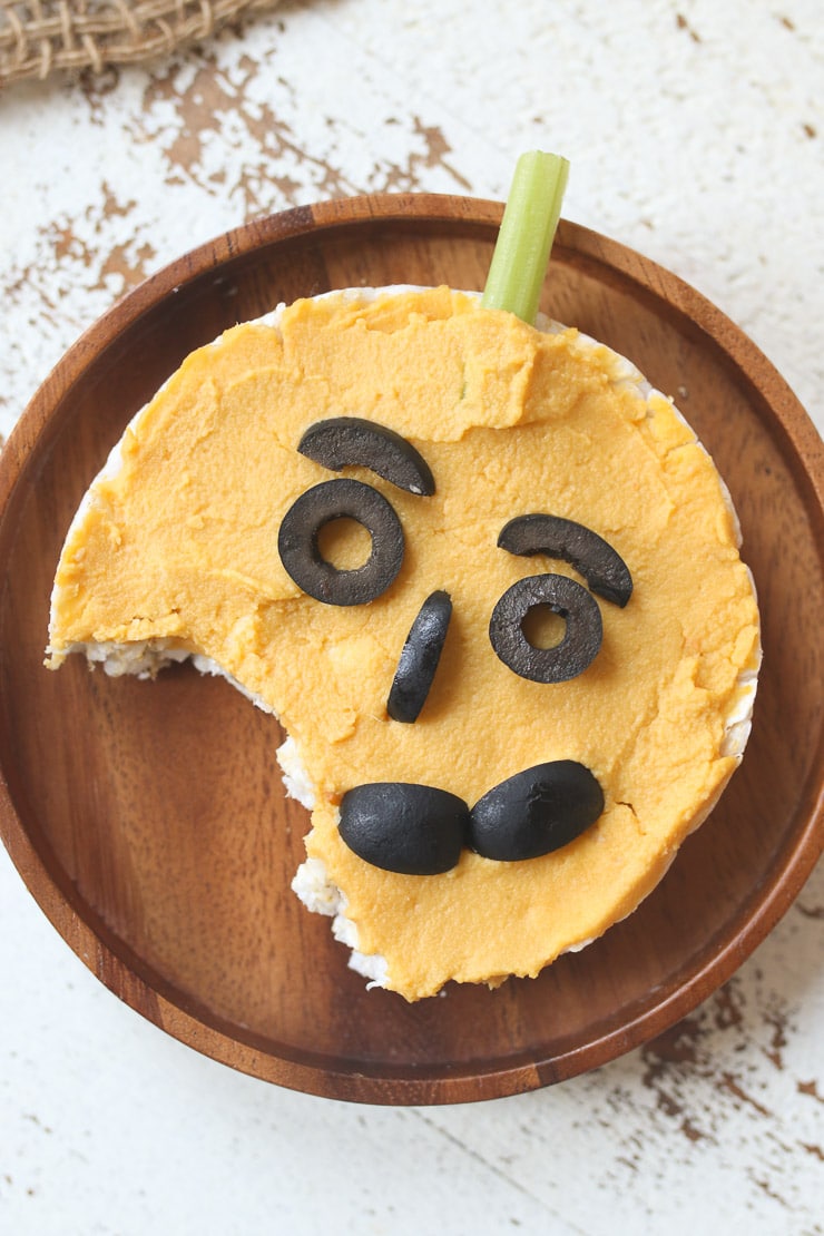Rice cake with pumpkin hummus with a bite taken out of it.