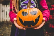 Girl holding pumpkin.