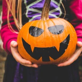 Girl holding pumpkin.