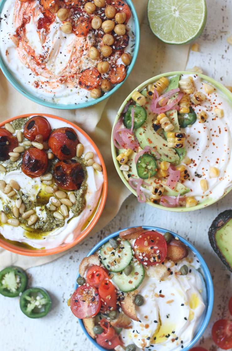 Four yogurt bowls with various savoury toppings. 