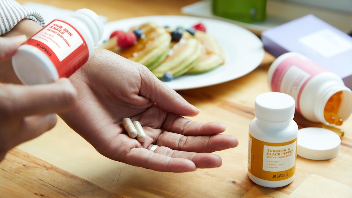 Hand taking diet supplements.