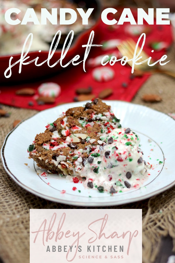 pinterest image of a Slice of cookie skillet on a white plate topped with ice cream and candy cane with text overlay