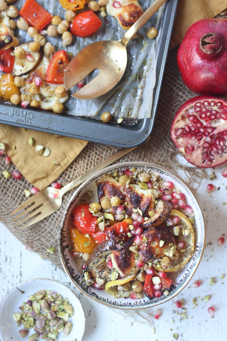 birds eye view of a variety of vegetables cooked on a sheet pan next to a bowl of vegetables garnished with fresh fruit. 