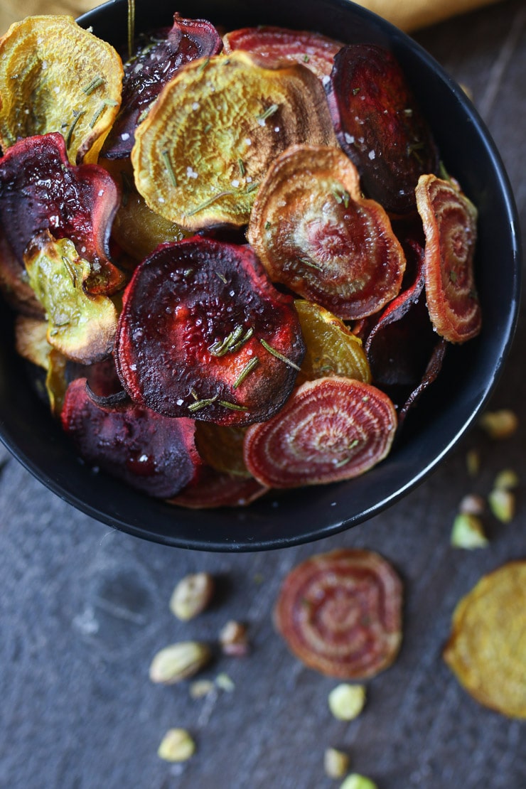 Birds eye view of colourful beet chips in a black bowl.