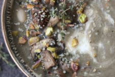 Bowl of mushroom soup topped with nuts and herbs.