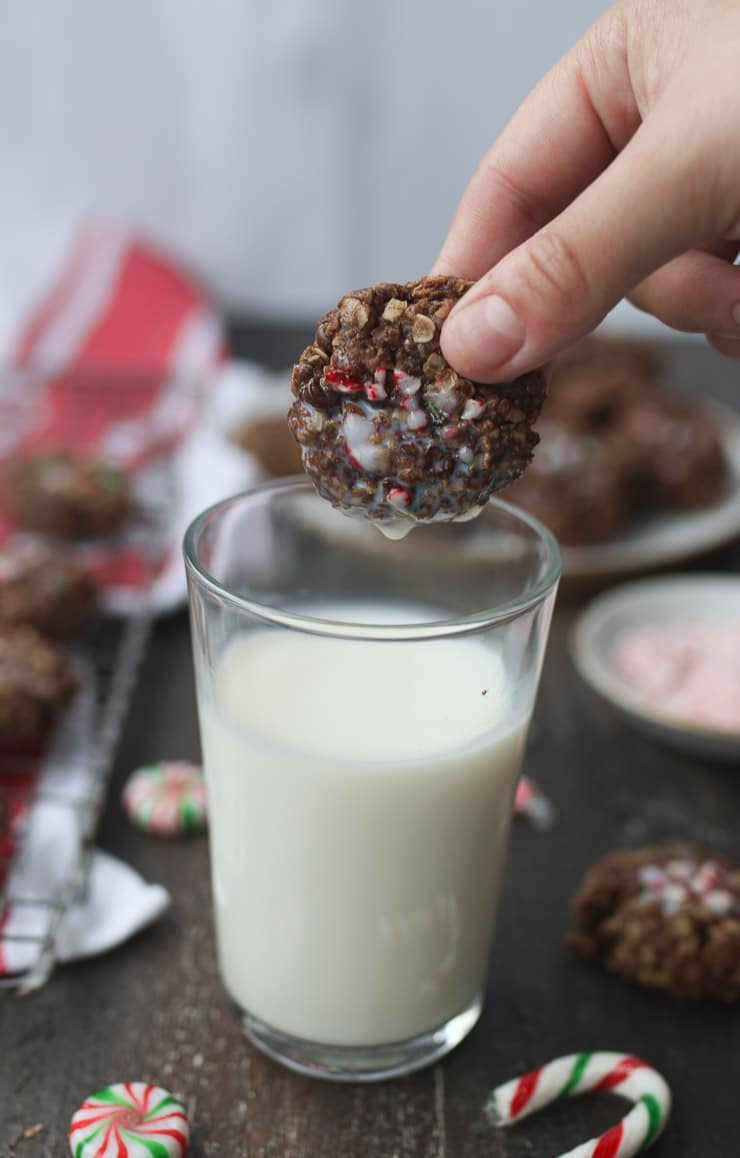 Hand dipping a cookie in a glass of milk. 