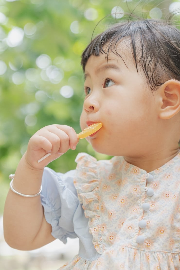 image of a baby looking sideways holding a lollipop